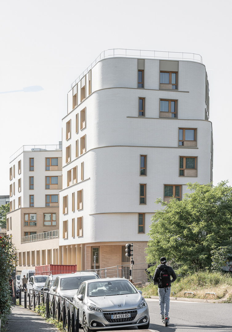 Bâtiment élégant, à la façade dynamique et arrondie teintes blanc beige et sable sur 7 niveaux à l'angle de deux rues